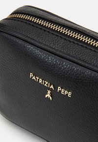 Černá kožená kosmetická taštička s zlatým zipem, raženým logem a texturovaným povrchem. Kompaktní obdélníkový tvar s hladkým interiérem.