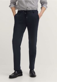 Granatowe spodnie z elastycznym pasem i sznurkiem, z bocznymi kieszeniami, dopasowanym krojem oraz gładkim, lekkim materiałem.