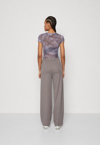 Grey wide-leg pants paired with a fitted tie-dye shirt. The shirt has short sleeves and a soft texture, while pants feature a smooth finish.