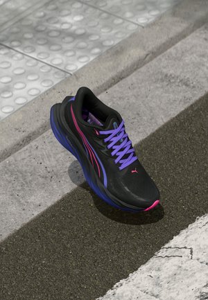 Baskets de sport noires avec des accents et des lacets violets. Dotées d'un dessus texturé, d'une semelle rembourrée et d'un logo proéminent sur le côté.