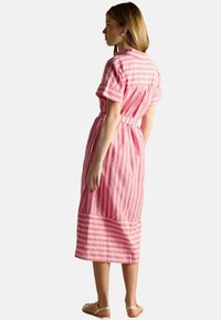 Rosa gestreiftes Kleid mit kurzen Ärmeln, einer taillierten Passform und einem knielangen Saum. Hergestellt aus einem strukturierten Stoff mit einem atmungsaktiven Design.