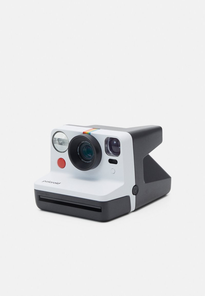 Polaroid camera with a white body, black accents, round lens, two flash bulbs, a red button, and a rainbow stripe across the top.