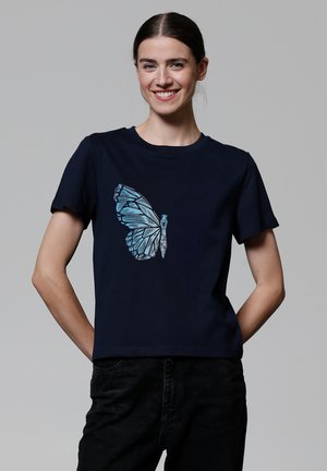 Marineblauwe katoenen T-shirt met een grote, lichtblauwe geometrische vlinderprint op de voorkant. Korte mouwen, ronde hals.