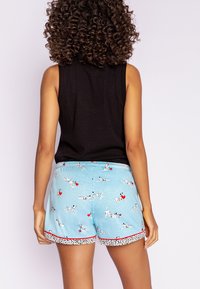 Lichtblauwe shorts met een speelse hondenprint, rode accenten en een stippenrand; gemaakt van een zachte, ademende stof.