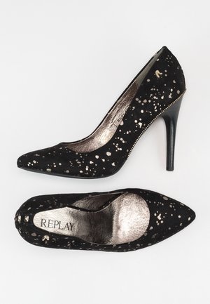 Tacones altos de ante negro con detalles plateados salpicados, punta afilada y forro metálico, con un tacón de aguja estrecho. Marca: Replay.