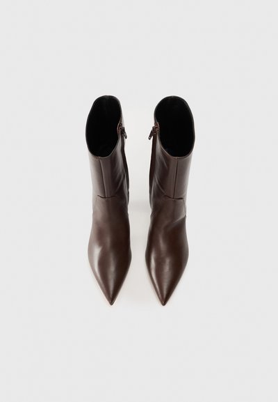 Brown leather ankle boots with a pointed toe, featuring a smooth texture and a side zipper for easy wear. Minimalist design and shape.