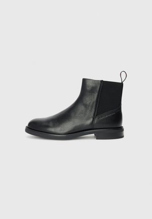 Botas de tobillo de cuero negro con paneles laterales elásticos, punta redondeada, tacón bajo cuadrado y una lengüeta en la parte posterior para ponerlas y quitar las fácilmente.
