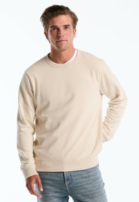 Beige sweatshirt met ronde hals, gemaakt van zachte stof met een ribbelkraag en -manchetten, met een klein logo op de borst en een relaxed fit.