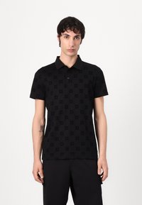 Svart polo-skjorte med et teksturert mønster med sirkulære motiver. Korte ermer, krage-design og knappestolpe. Glatt stofffinish.