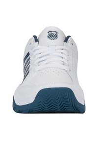 White athletic shoes with navy accents, lace-up design, perforated details, and a textured rubber sole featuring a zigzag pattern. K-Swiss logo on tongue.