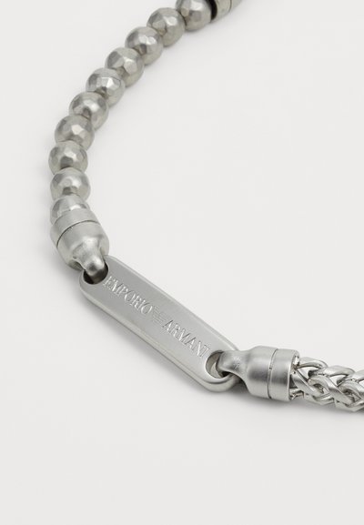 Silverfärgad armband gjort av texturerade pärlor och släta länkar. Har en lås med "Emporio Armani" ingraverat på en rektangulär märkning.
