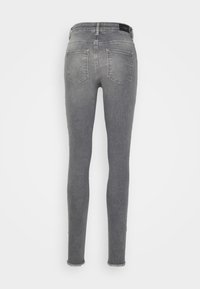 Jeans cinza slim-fit com um clássico design de cinco bolsos, bainha ligeiramente desfiada e uma textura de denim suave. Vista traseira exibida.