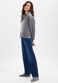 Gray striped corduroy shirt, long sleeves, relaxed fit. Paired with wide-leg dark blue jeans and gray slip-on shoes.