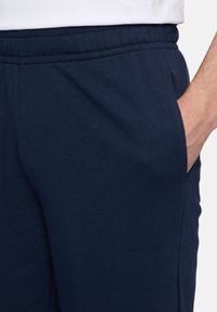 Marineblauwe sweatpants met een zachte textuur, voorzien van zijzakken en een elastische tailleband voor comfort en gemakkelijke pasvorm.