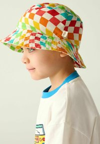 Kolorowa czapka typu bucket w kratę w kolorach czerwonym, pomarańczowym, zielonym i żółtym, wykonana z tkaniny, z szerokim rondem i metką z boku.