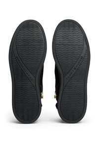 Suelas de goma negra con patrones ondulados texturizados, con el nombre de la marca "TOMMY HILFIGER" en relieve. Acentos de cremallera y herrajes en los lados.