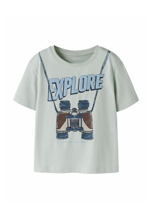 Light green t-shirt with a binoculars graphic hanging on a strap and the word "EXPLORE" above it in large blue letters.