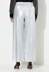 Silverfärgade vida byxor med en glänsande, slät yta; elastisk midja; ihop med svarta högklackade skor.