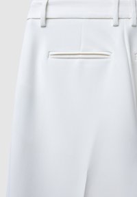 Weiße Hose aus strukturiertem Stoff, mit flachem Vorderteil und zwei Gesäßtaschen. Enthält Gürtelschlaufen und einen klaren, maßgeschneiderten Schnitt.