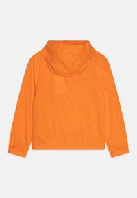 Pomarańczowa kurtka wiatrówka z kapturem, elastycznymi mankietami i dołem, o gładkiej fakturze i prostym, nieozdobionym wzorze.