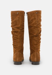 Bottes en suède marron à hauteur de genou avec une finition texturée, un design décontracté, deux fermetures éclair à l'arrière et une semelle en caoutchouc noir plat.