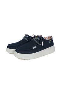 Marineblaue Segeltuchschuhe mit einer weißen Gummisohle, im Slip-On-Design, grauen Schnürsenkeln und einem bunten gemusterten Innenfutter.