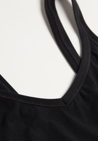 Zwarte sporttanktop met een V-hals ontwerp, gemaakt van soepel, stretch stof. Voorzien van versterkte naden en verstelbare bandjes.
