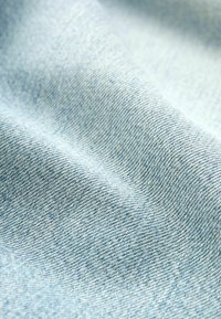 Svetlomodrá denimová látka s hladkou textúrou, zobrazeným jemným tkaným vzorom. Vlákna sú úzko prepletené, čo mu dodáva mäkký vzhľad.