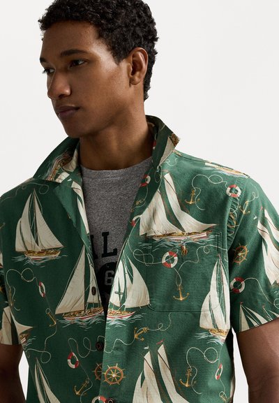 Groene shirt met korte mouwen met een patroon van zeilboten, reddingsboeien en ankers. Gemaakt van lichtgewicht stof met een relaxte kraag.