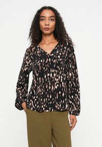 Sort bluse med geometrisk mønster i pink og hvid; V-udskæring, lange ærmer med samlet manchet, glat stoftekstil.