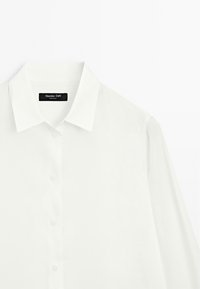 White button-up shirt with a classic collar, long sleeves, and a smooth texture. Features a black label with the brand name "Massimo Dutti."