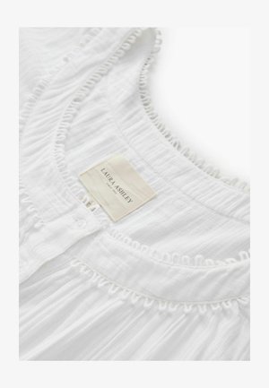 Weißes Kleidungsstück mit strukturierter Stoffqualität, mit einem gerafften Ausschnitt, Knopfleiste und einem Etikett mit der Aufschrift "Laura Ashley" zur Markenkennzeichnung.