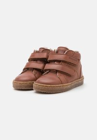 Chaussures pour enfants en cuir marron avec deux scratchs, bout arrondi et semelle en caoutchouc à motif texturé. Doublées pour plus de confort.