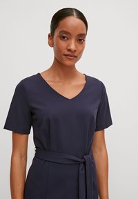 Navy V-Ausschnitt-Kleid mit kurzen Ärmeln, aus glattem Stoff gefertigt, verfügt über einen gebundenen Taillengürtel zur Betonung. Einfaches und elegantes Design.