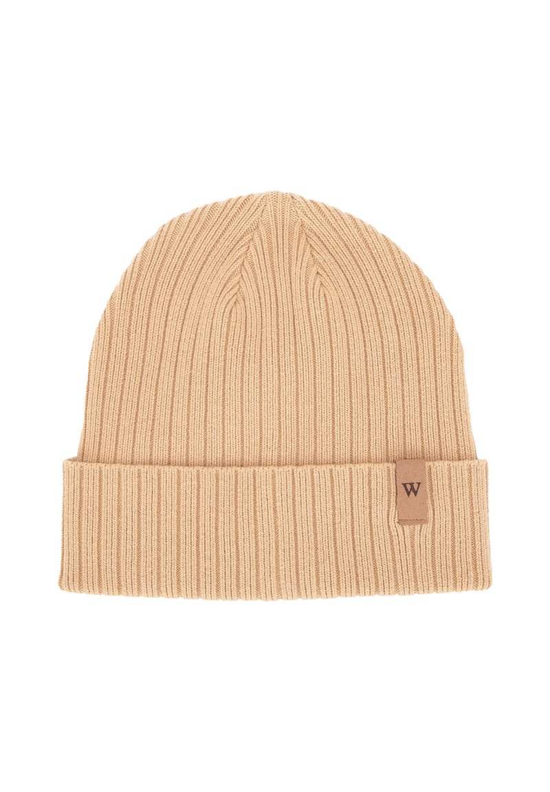 Beige geribbelde gebreide beanie met een opgevouwen boord en een klein bruin leren label met de letter "W". Zacht textuur en warm ontwerp.