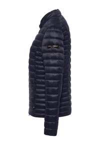 Marineblauwe pufferjack met horizontale gewatteerde print, ritszakken en een staande kraag. Het materiaal lijkt glad en heeft een logo op de mouw.