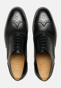 Scarpe eleganti in pelle nera con dettagli brogue, caratterizzate da una finitura liscia, una punta sagomata e un design con laccio. Elementi di design classici ed eleganti.