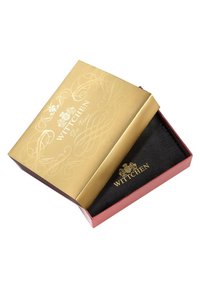 Gouden en rode presentatiedoos met een decoratief reliëfontwerp en logo. Binnenin bevindt zich een zwarte textured compartiment voor een item.