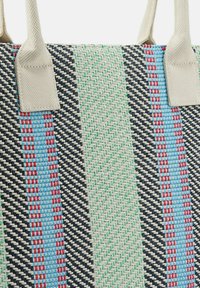 Borsa tote intrecciata con strisce multicolori in blu, verde, rosso e nero. Presenta manici beige robusti e una superficie texturizzata.
