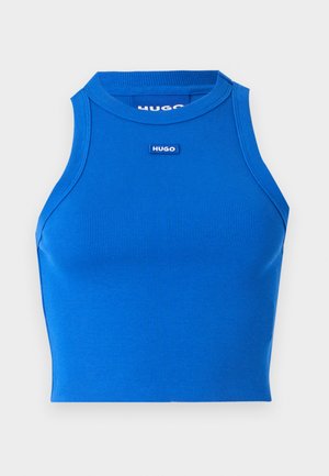 Modra rebrovana brezrokavnica s kratkim krojem in visokim ovratnikom. Ima majhen kontrastni logotip blagovne znamke na sredini. Gladka tekstura, prilega se telesu.