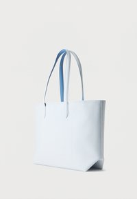 Sac cabas en cuir texturé bleu clair avec deux poignées fines, posé debout sur un fond blanc uni.