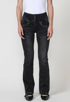 Black denim jeans with a fitted waist, five-button closure, decorative studs on pockets, and a flared leg design. Smooth texture.