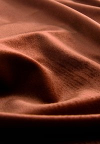 Brown fabric with a soft, textured surface, displaying gentle waves and folds. The material appears lightweight and pliable.