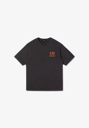 T-shirt nera a maniche corte con un piccolo logo di peperoncino rosso e verde e testo giallo "STAN RAY" sul petto sinistro.