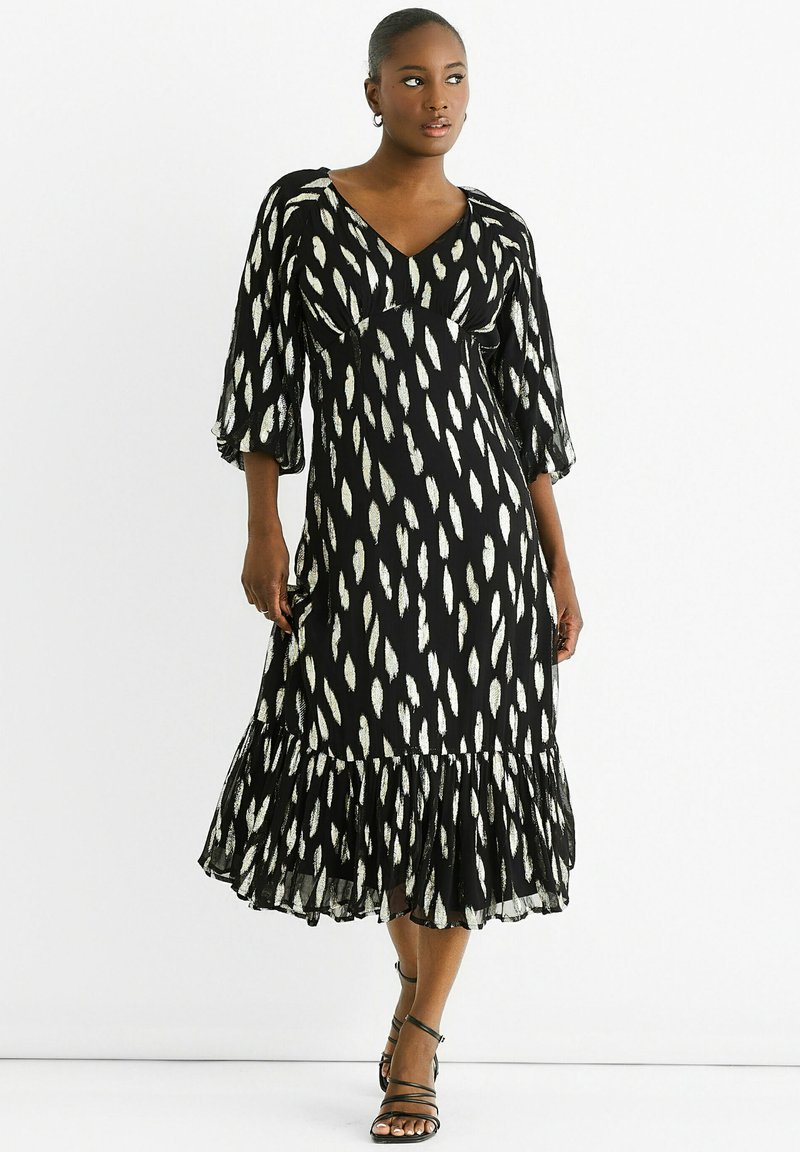 Black maxi dress with white leaf pattern, V-neckline, three-quarter sleeves, and ruffled hem. Lightweight fabric with flowing texture.