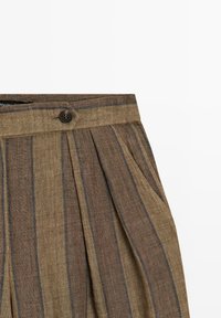 Brune linnedbukser med lodrette mørke striber, læg, sidelomme og knaplukning ved taljen.