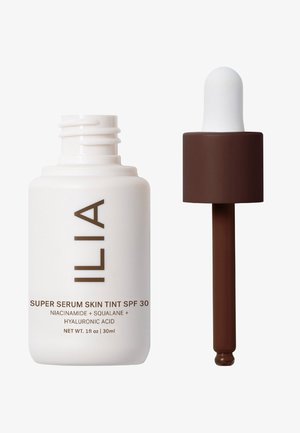 ILIA Super Serum Skin Tint SPF 30 in un flacone bianco con testo marrone, presenta un tappo contagocce ed è di 30 ml di volume.