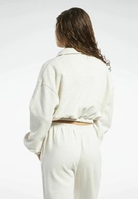 Hellgrau geschnittenes Sweatshirt mit Fallarmen, elastischem Bund und weicher Textur, kombiniert mit passenden, hoch taillierten Sweatpants.