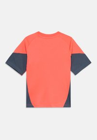 Camisa de manga curta com design em block color coral e azul marinho. Textura suave com gola redonda e mangas raglan, detalhe de costura mínimo.