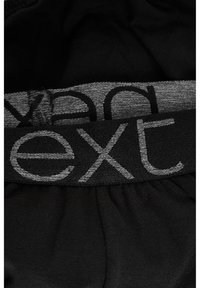Schwarzer Stoff mit grauem elastischem Bund, auf dem das Wort "next" in einer kräftigen, modernen Schriftart angezeigt wird; glatte Textur mit einem leichten Glanz.